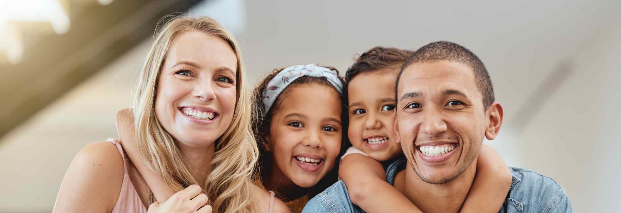 Close-up of family of four smiling together | Hemmat Law Group