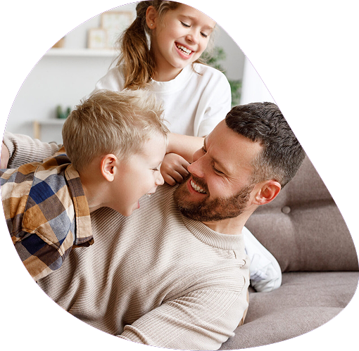 Smiling father relaxing on sofa with his son and daughter | Hemmat Law Group