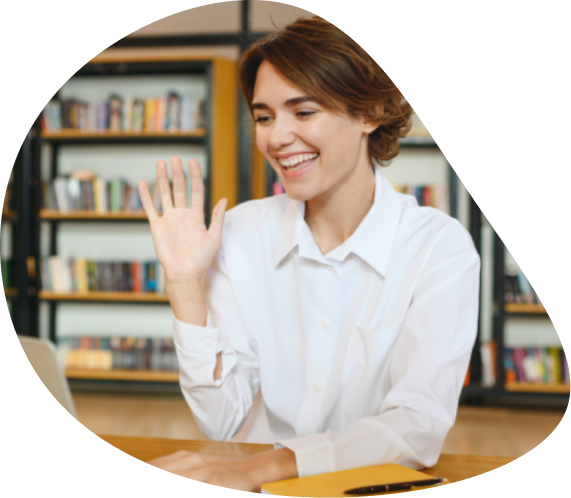Young woman waving during a video call from a library | Hemmat Law Group