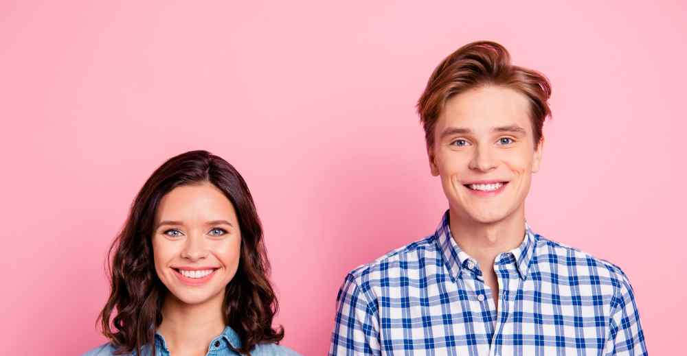 Smiling couple posing against pink background | Hemmat Law Group