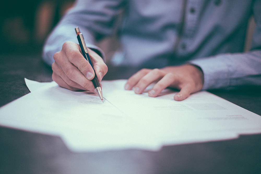 Man signing a legal document at desk | Hemmat Law Group