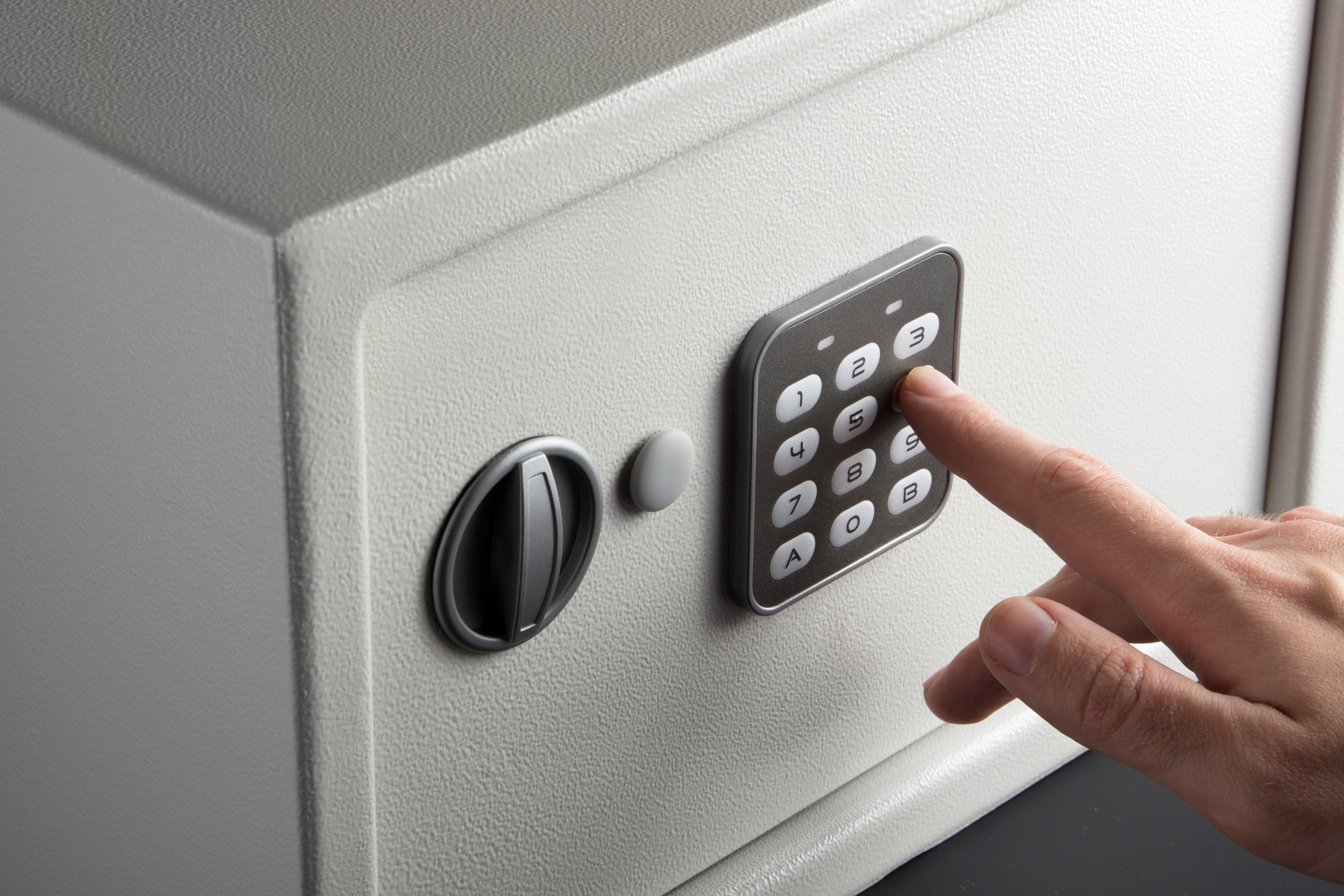 The hand opens a combination lock on the safe, a light safe on a dark background